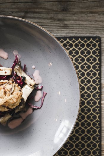 Wellnesshotel in Südtirol: Auf in den Traumurlaub! Kreativ angerichtetes Gourmetgericht mit Pilzen und Sauce in grauer Schüssel