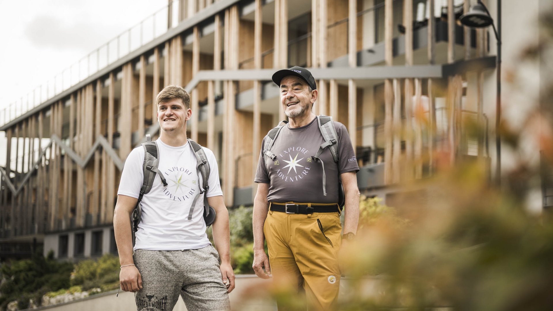 Weekly programme of the “Wanderhotels Südtirol” Young and older man with backpacks in front of modern building