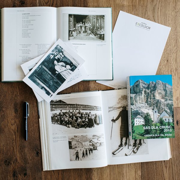 Wellnesshotel in Südtirol: Auf in den Traumurlaub! Aufgeschlagene Bücher mit alten Fotos und ein Stift auf Holztisch