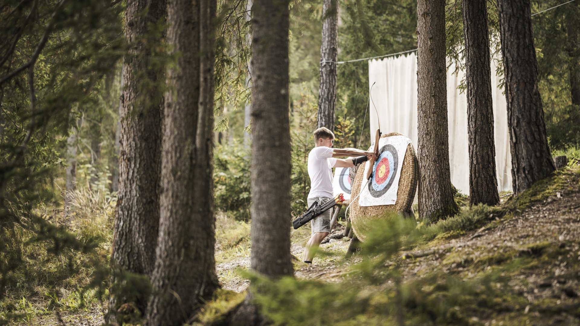 Weekly programme of the “Wanderhotels Südtirol” Man pulling arrow from archery target in forest