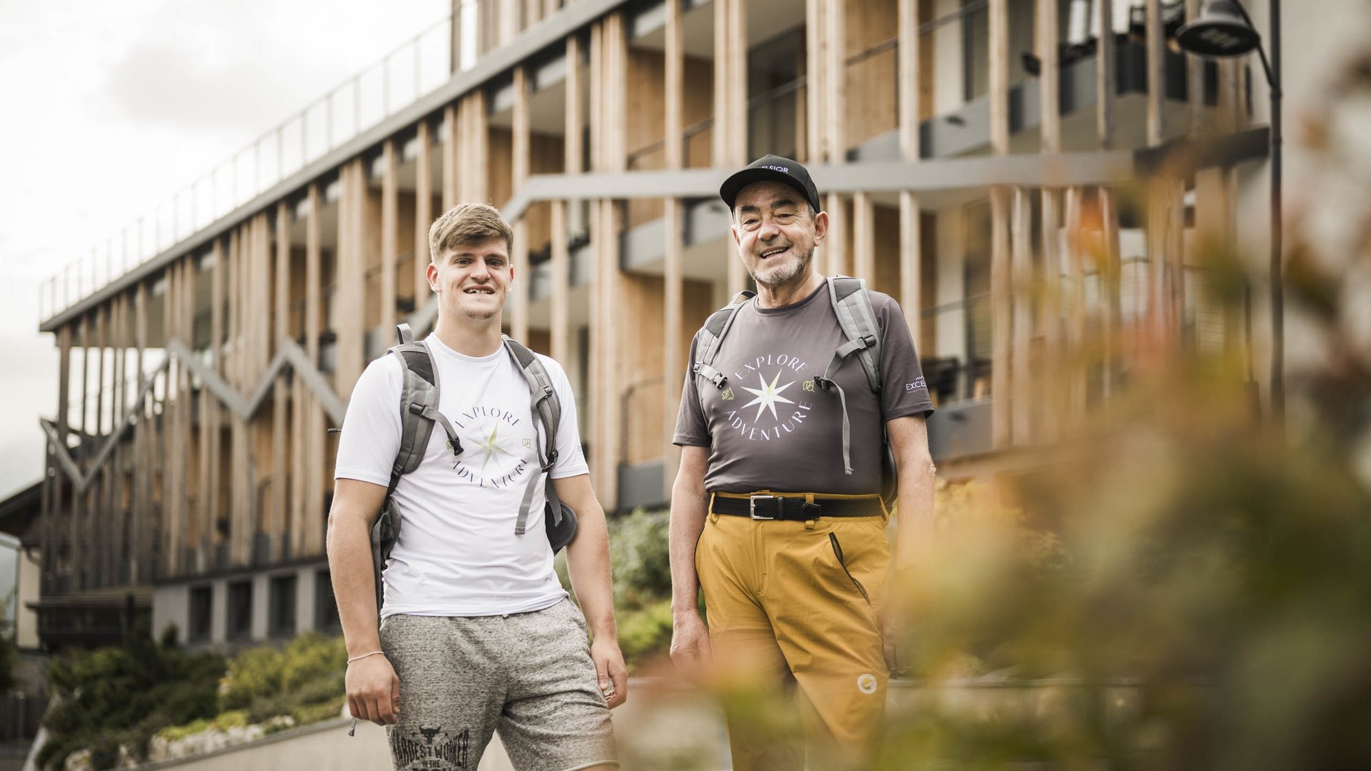 Weekly programme of the “Wanderhotels Südtirol” Two men with backpacks standing outside a modern building