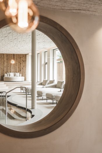 Wellnesshotel in Südtirol: Auf in den Traumurlaub! Spiegel mit Blick auf den stilvollen Spa-Bereich mit Pool und Sitzgelegenheiten