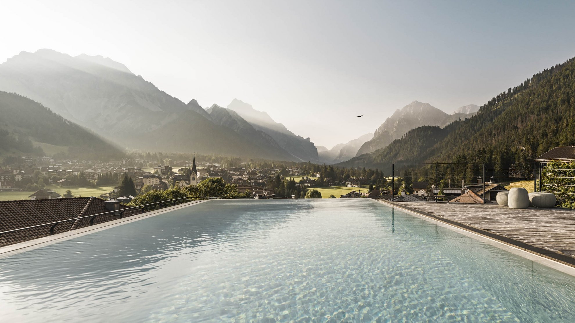 Angebote: Wellness und Wandern | Südtirol Infinity-Pool mit Blick auf Dorf und Berge im Nebel