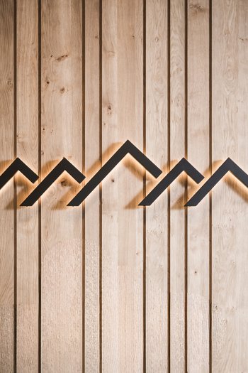 Wellnesshotel in Südtirol: Auf in den Traumurlaub! Hinterleuchtetes Wanddekor mit Bergsilhouetten aus Holzpaneelen