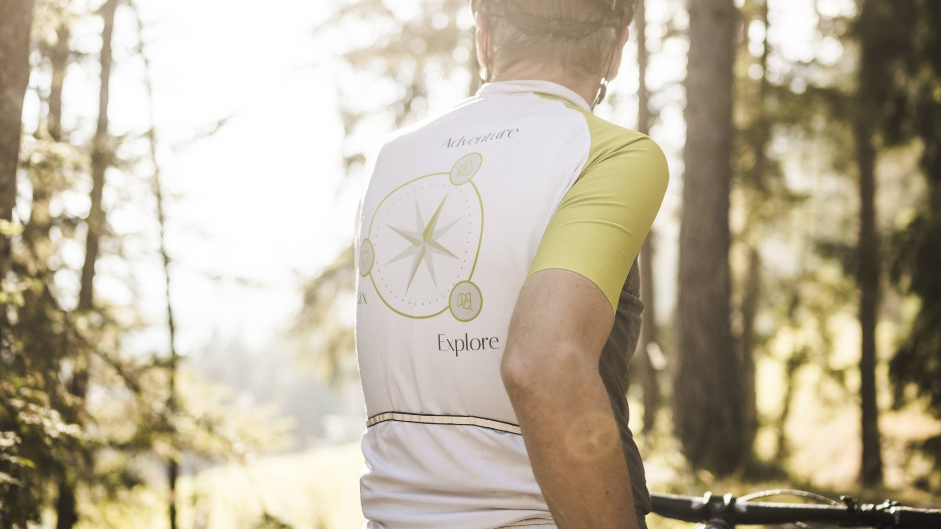 Weekly programme of the “Wanderhotels Südtirol” Cyclist in forest wearing white and yellow jersey with compass design