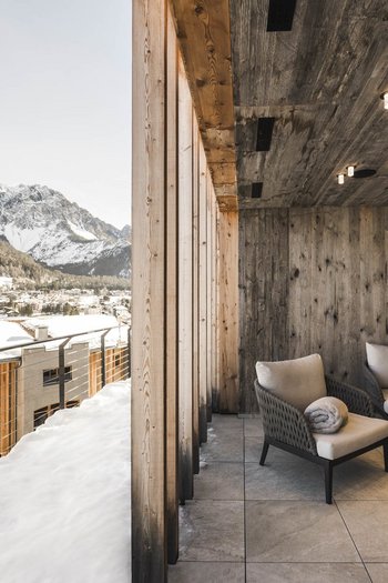 Wellnesshotel in Südtirol: Auf in den Traumurlaub! Gemütliche Terrasse mit Holzdecke und Bergblick im verschneiten Dorf