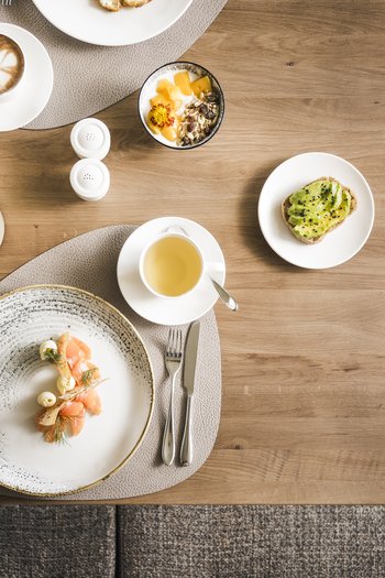 Wellnesshotel in Südtirol: Auf in den Traumurlaub! Verschiedene Frühstücksgerichte und Getränke auf einem Holztisch