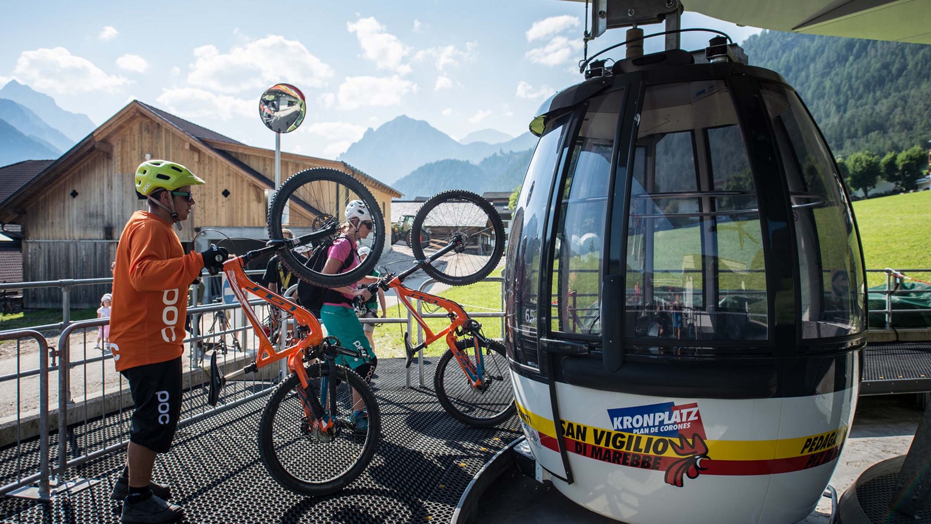 Bike-Leistungen Zwei Radfahrer tragen ihre Mountainbikes zur Bergbahn in den Alpen