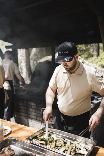 Weekly programme of the “Wanderhotels Südtirol” Man in black cap grilling zucchini in metal trays