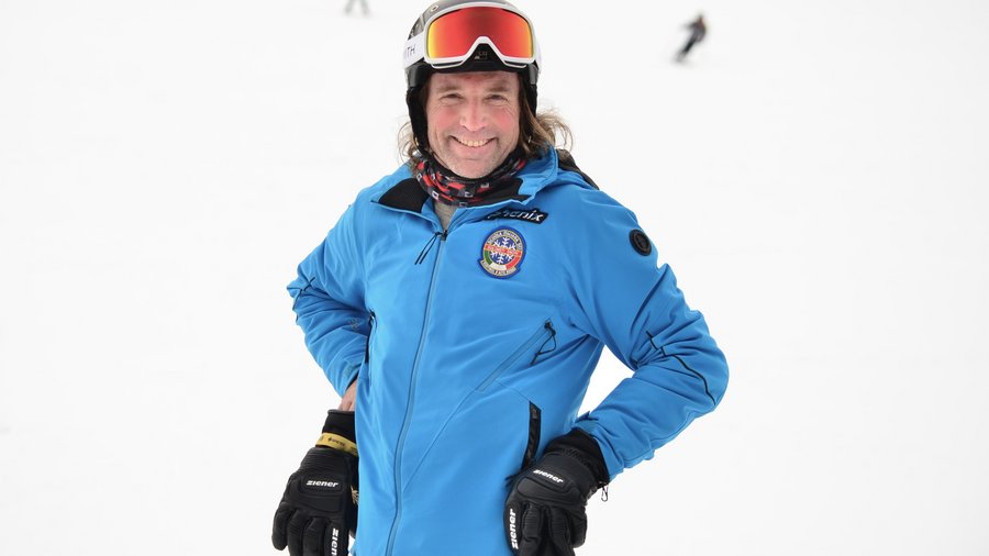 Il nostro hotel sulle piste a San Vigilio di Marebbe Uomo con giacca da sci blu e casco sorride sulla pista innevata