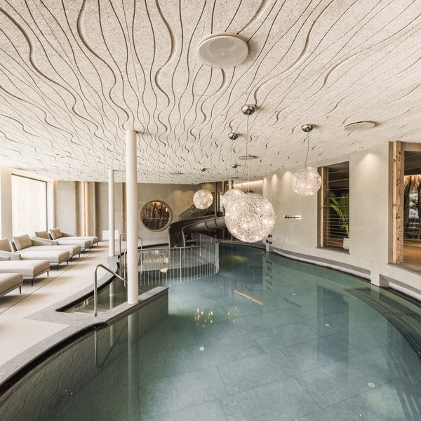 Wellnesshotel in Südtirol: Auf in den Traumurlaub! Moderner Innenpool mit Liegen und dekorativen Hängelampen