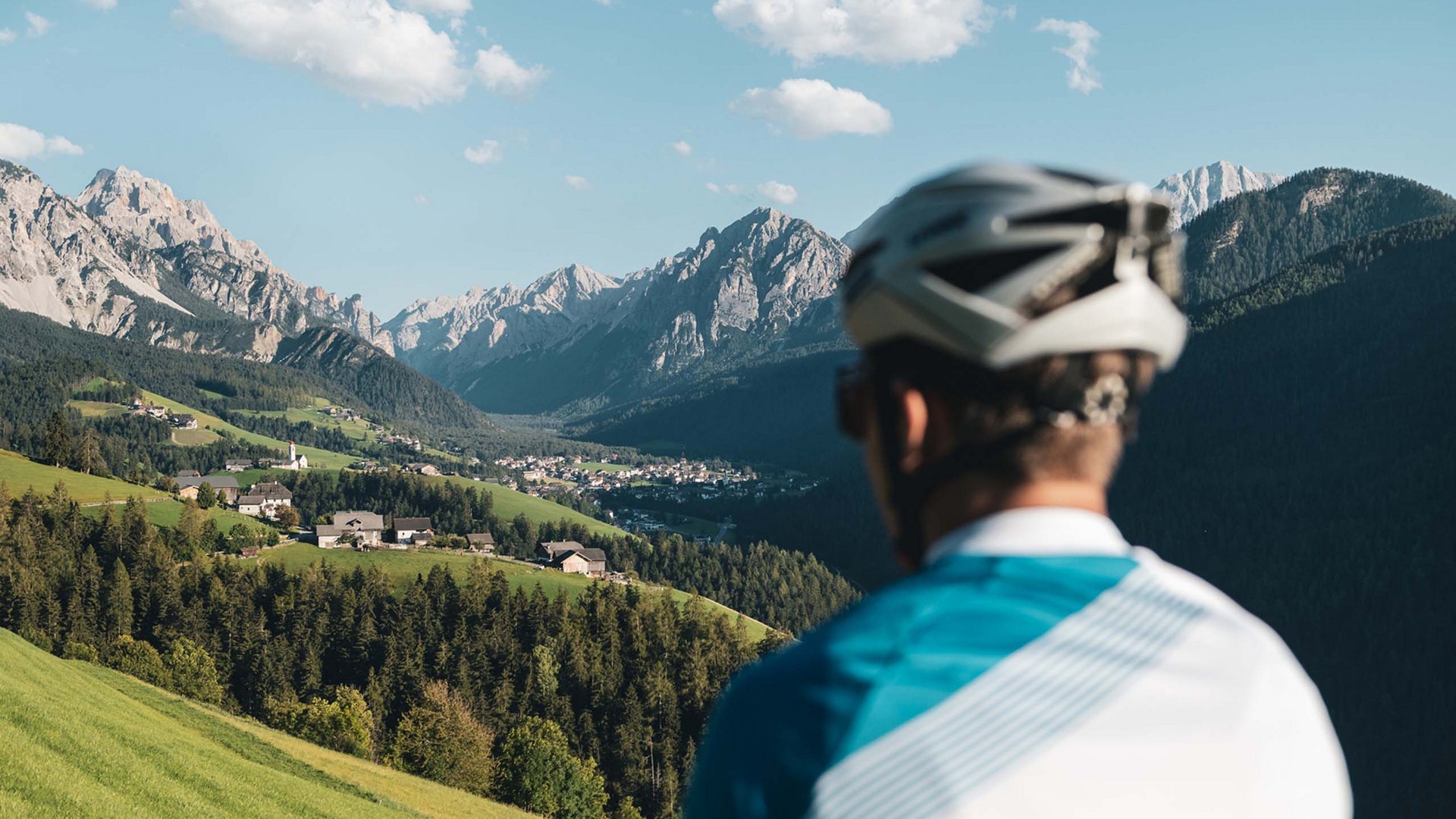 Bike-Leistungen Radfahrer blickt auf ein Tal mit Bergen und Dörfern bei klarem Himmel